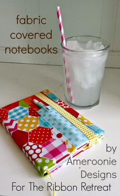 a book and glass on a table with the title fabric covered notebooks by ameroonie designs for the ribbon retreat