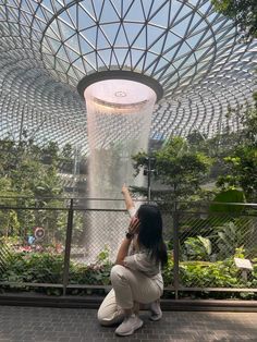 a woman kneeling down in front of a water fountain at the gardens by the bay