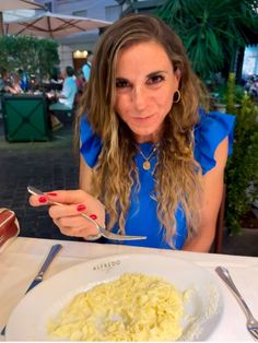 a woman sitting at a table with a plate of food and fork in front of her