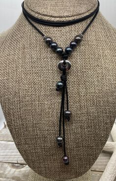 Boutique and Chic Leather and Freshwater Peacock Pearl Necklace. This necklace was hand knotted and created on a beautiful dyed noire black leather.  This leather is a 2mm cord that is soft and supple. The necklace will go with any coastal or boho clothing and it is modern and trendy to wear with business casual as well as a simple tee and jeans. It would also look great with any western style of clothing. The leather has been barrel knotted. As with all leathers, there is some distressing and the leather will continue to distress as it is worn- this is intended. The center of attention is the bali pewter 16mm metal ring that serves as a connector.  There are 10 freshwater cultured peacock pearls that have been strung and knotted at the top of the necklace. (The pearls are 8mm in size and Black Bohemian Necklace With Sliding Knot, Black Hand Knotted Adjustable Necklace, Adjustable Black Hand Knotted Necklace, Peacock Pearls, Peacock Pearl, Choker Style Necklace, Bali Silver, Chic Leather, Simple Tees