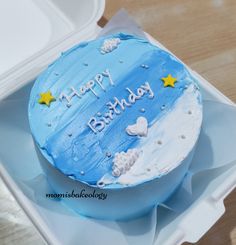 a blue birthday cake sitting on top of a plastic container filled with frosting and stars