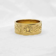 men's buddhist lotus flower om mani padme hum ring 2 made in 14k solid gold or 18k solid gold ॐ मणि पद्मे हूँ (english: om mani padme hum) that is the six-syllabled  sanskrit mantra and a lotus flower is on the side of it. - width 8.7mm - materials: real 14k solid gold, real 18k solid gold - free shipping on all orders - designed by carre d'or - made in south korea 14k gold ring weight 6.5 US 6.56g (±3%) 7.0 US 6.80g (±3%) 7.5 US 6.92g (±3%) 8.0 US 7.04g (±3%) 8.5 US 7.34g (±3%) 9.0 US 7.42g (±3%) 9.5 US 7.53g (±3%) 10.0 US 7.66g (±3%) 10.5 US 7.79g (±3%) 11.0 US 8.04g (±3%) 11.5 US 8.15g (±3%) 12.0 US 8.28g (±3%) 12.5 US 8.41g (±3%) 13.0 US 8.52g (±3%) 18k gold ring weight 6.5 US 7.81g (±3%) 7.0 US 8.10g (±3%) 7.5 US 8.25g (±3%) 8.0 US 8.39g (±3%) 8.5 US 8.75g (±3%) 9.0 US 8.84g (±3%) 9.5 Spiritual 14k Gold Engraved Ring, Spiritual Engraved 14k Gold Ring, Spiritual Yellow Gold Engraved Ring In Brass, Spiritual Engraved Yellow Gold Ring In Brass, Spiritual Yellow Gold Engraved Brass Ring, Spiritual Engraved Ring For Anniversary, Spiritual Engraved Wedding Ring, Symbolic Yellow Gold Jewelry For Puja, Yellow Gold Ring For Puja