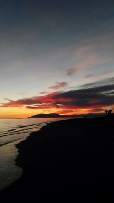 the sun is setting over the ocean and beach