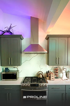 a kitchen with an oven, microwave and counter tops in grey cabinets next to a purple light