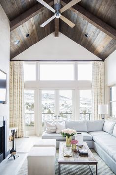 a living room with couches, tables and a ceiling fan in the middle of it