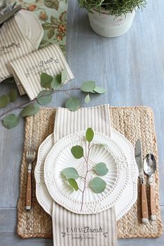 a place setting with plates, silverware and greenery