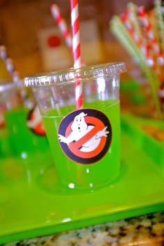 a green cup with a red and white striped straw sticking out of it's side