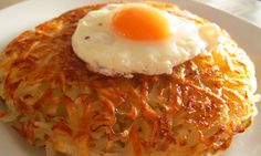 a close up of a plate of food with hash browns and an egg on top