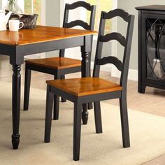 a dining room table with two chairs and a cabinet in the corner next to it