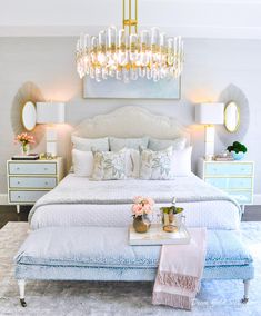 a bedroom with a large bed, chandelier and two nightstands on either side