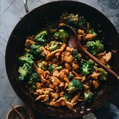 chicken and broccoli stir frying in a skillet with wooden spoons