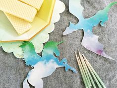 some paper cut outs with unicorns and clouds on them next to paintbrushes