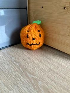 an orange stuffed pumpkin sitting on the floor next to a door way with its eyes closed