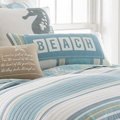 a bed with blue and white striped comforter, pillows and pillow cases on it