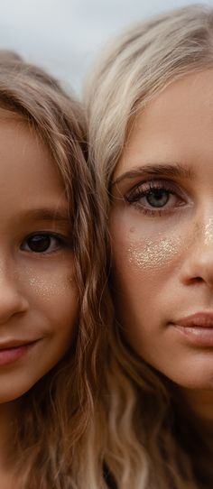 two beautiful young women standing next to each other with their faces covered in gold glitter