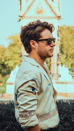 a man wearing sunglasses standing in front of a clock tower