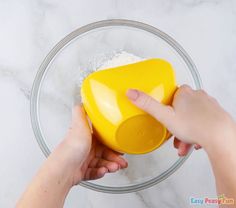 someone is mixing ingredients in a bowl with their hand on the side and another person's arm reaching for it