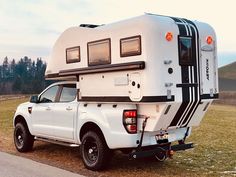 a white truck with a camper attached to it's bed parked on the side of a road