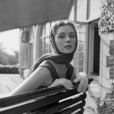 black and white photograph of a woman sitting on a bench wearing a scarf over her head