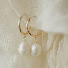 Designer: OFINA An everyday classic. Polished pearl mini hoops to give you a classic modern look. Available in 2 sizes. Small Size: 15mm Hoop w/ 7-8mm Freshwater Pearl Large Size: 18mm Hoop w/ 10mm Freshwater Pearl Material & Care 14k Gold Filled Stone: Freshwater Pearl Hypoallergenic Can be worn in water For more info: Jewelry Care How to Wear Lovely alone or stack the two sizes together. Can also be paired with your favorite huggies and studs! Luxury Small Hoop Pearl Drop Earrings, Cheap Hoop Earrings With Pearl Charm, Luxury Everyday Pearl Hoop Earrings, Classic Pearl Huggie Jewelry, Classic White Huggie Pearl Earrings, Classic Pearl Charm Huggie Earrings For Anniversary, Classic Pearl Huggie Earrings With Pearl Charm, Classic Pearl Hoop Huggie Earrings, Minimalist Small Hoop Pearl Drop Earrings