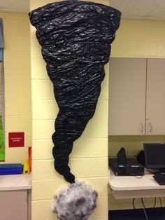 an office cubicle decorated with black plastic wrap and a white cloud hanging from the wall