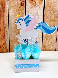 a paper cut out of a unicorn riding on top of a blue and white box