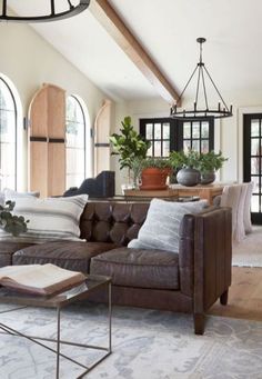 a living room filled with lots of furniture next to two large windows and a chandelier