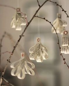 an ornament hanging from a tree branch with book pages attached to the branches