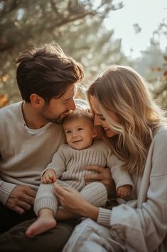 a man and woman holding a baby in their arms while sitting next to each other