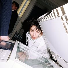 a woman is looking through the glass in front of a laptop computer that's being held by a man