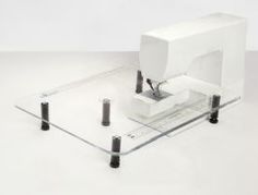 a white sewing machine sitting on top of a glass table next to a measuring tape