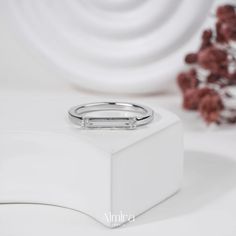 a diamond ring sits on top of a white box next to some dried red flowers