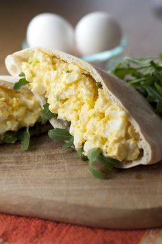 an egg burrito is cut in half on a cutting board next to some eggs