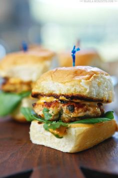 two sandwiches sitting on top of a wooden table with toothpicks stuck in them