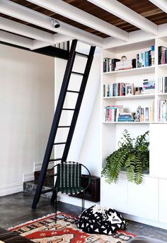 a living room with bookshelves and a ladder