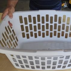 a person holding a white laundry basket on top of a wooden table