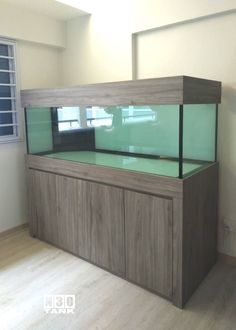 a fish tank sitting on top of a wooden cabinet next to a window in an empty room