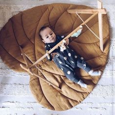 a baby laying on top of a brown blanket next to a wooden stick and arrow