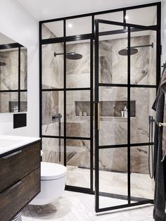 a modern bathroom with marble tile and glass doors