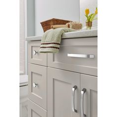 a bathroom with white cabinets and a basket on the top of the cabinet door handles