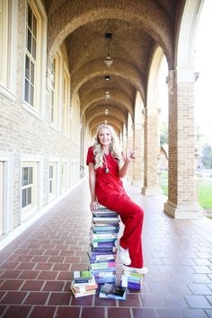 a woman sitting on top of a stack of books