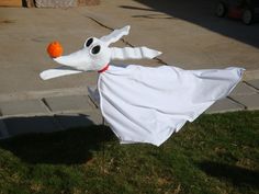 a dog dressed as a ghost with an orange ball in its mouth