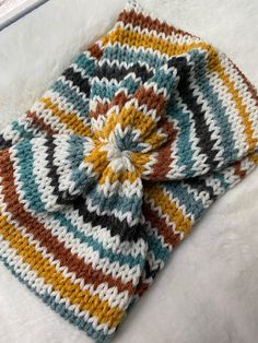 a multicolored crocheted blanket laying on top of a white furnishing