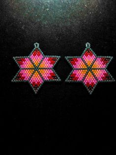 two pink and green beaded stars on black background