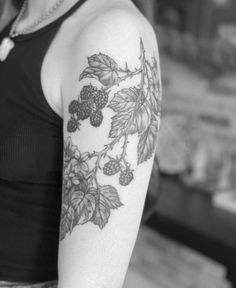 a black and white photo of a woman's arm with grapes on it