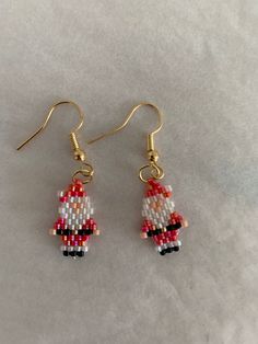 a pair of beaded santa claus earrings on a white tablecloth with gold earwires