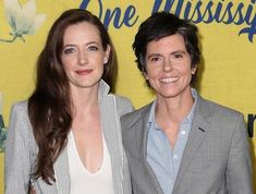 two women standing next to each other in front of a yellow wall with the words one mississippi written on it