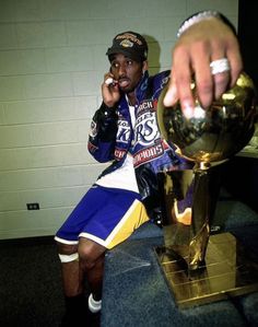 a man sitting on top of a table next to a trophy