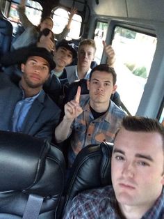 a group of young men sitting in the back of a bus with their fingers up