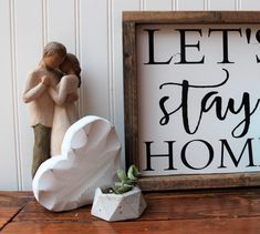 a wooden sign that says let's stay home next to a small potted plant